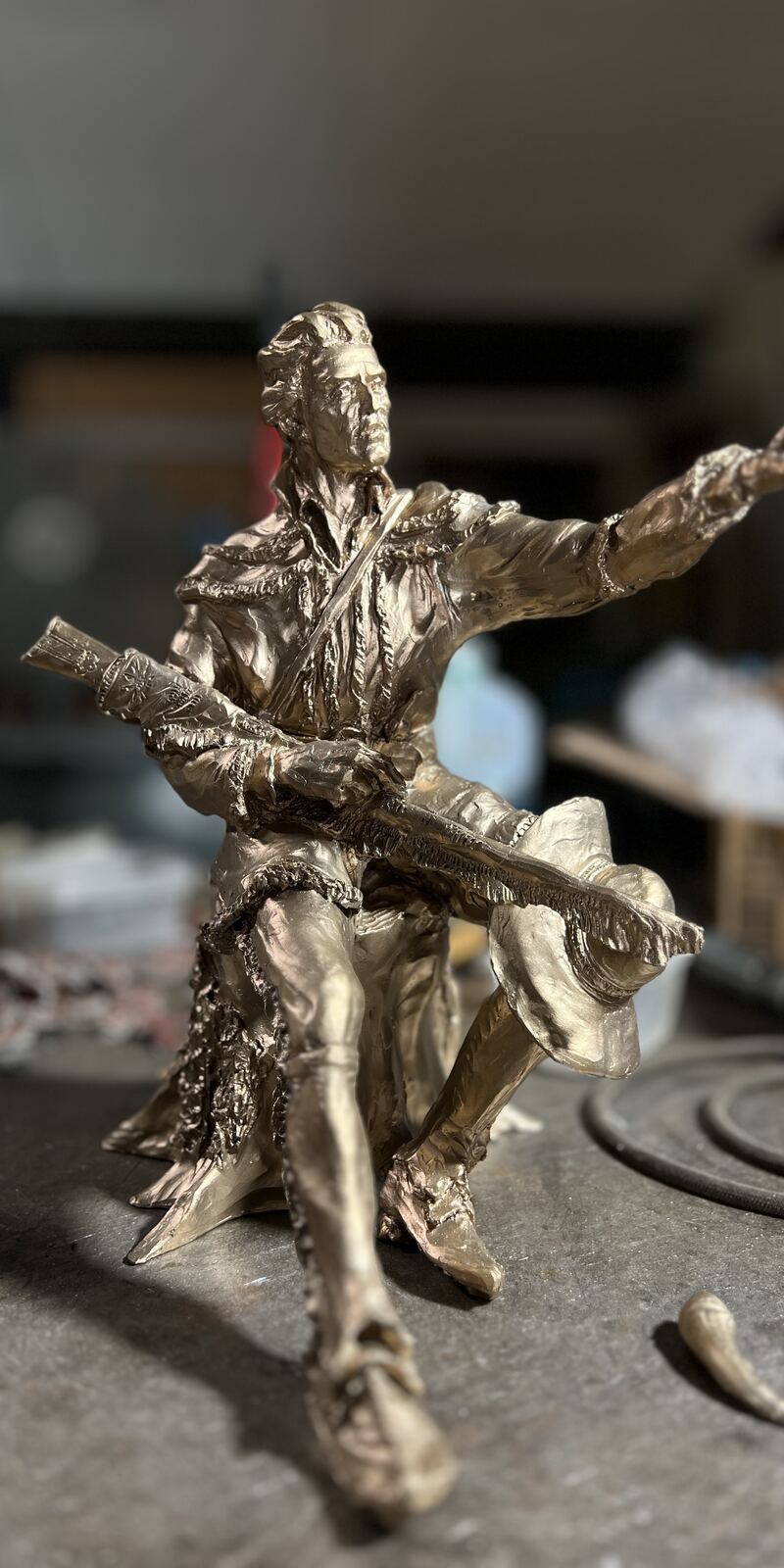 Bronze frontiersman holding a rifle, on the workbench during finishing