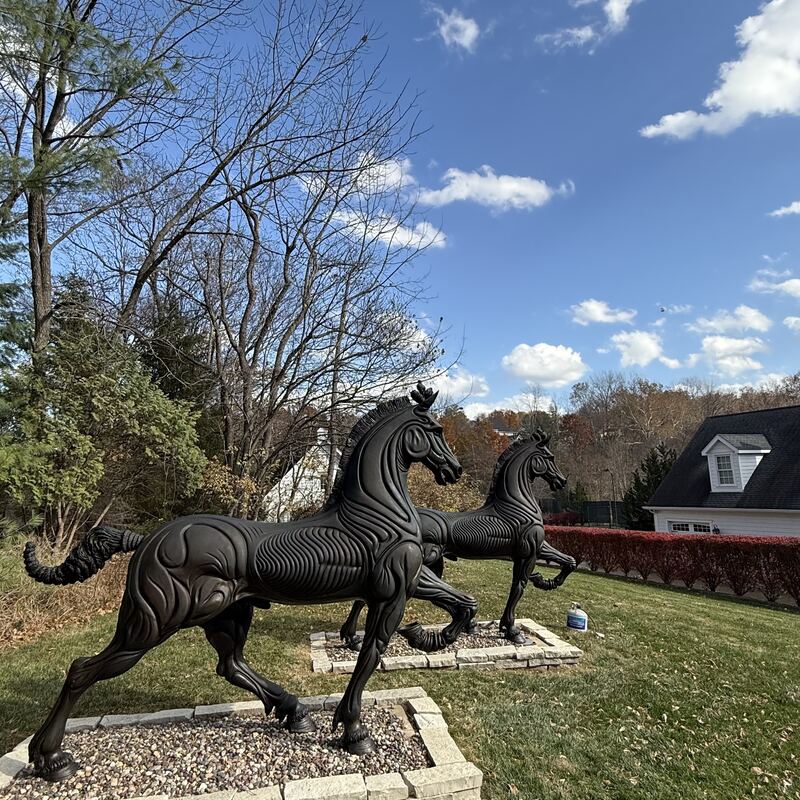 Life-size bronze horses installed on an open lawn