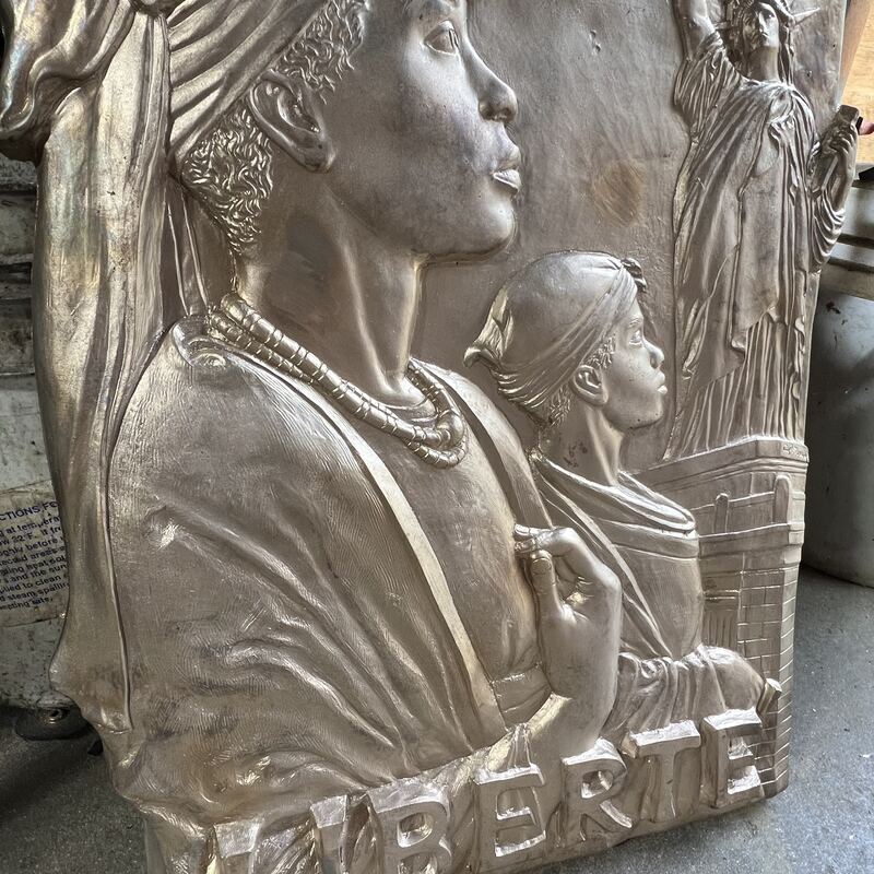 Bronze relief panel of a woman and child above the word Liberte