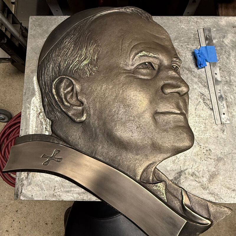 Bronze relief portrait of an older man on the workbench