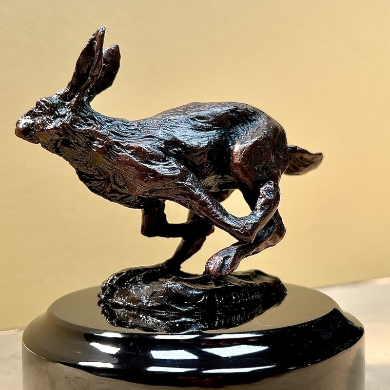 Bronze hare in mid-leap on a polished black base