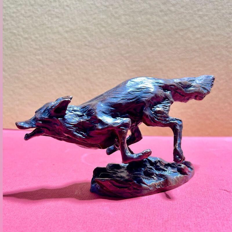 Small bronze of a wolf in full stride on a rocky base