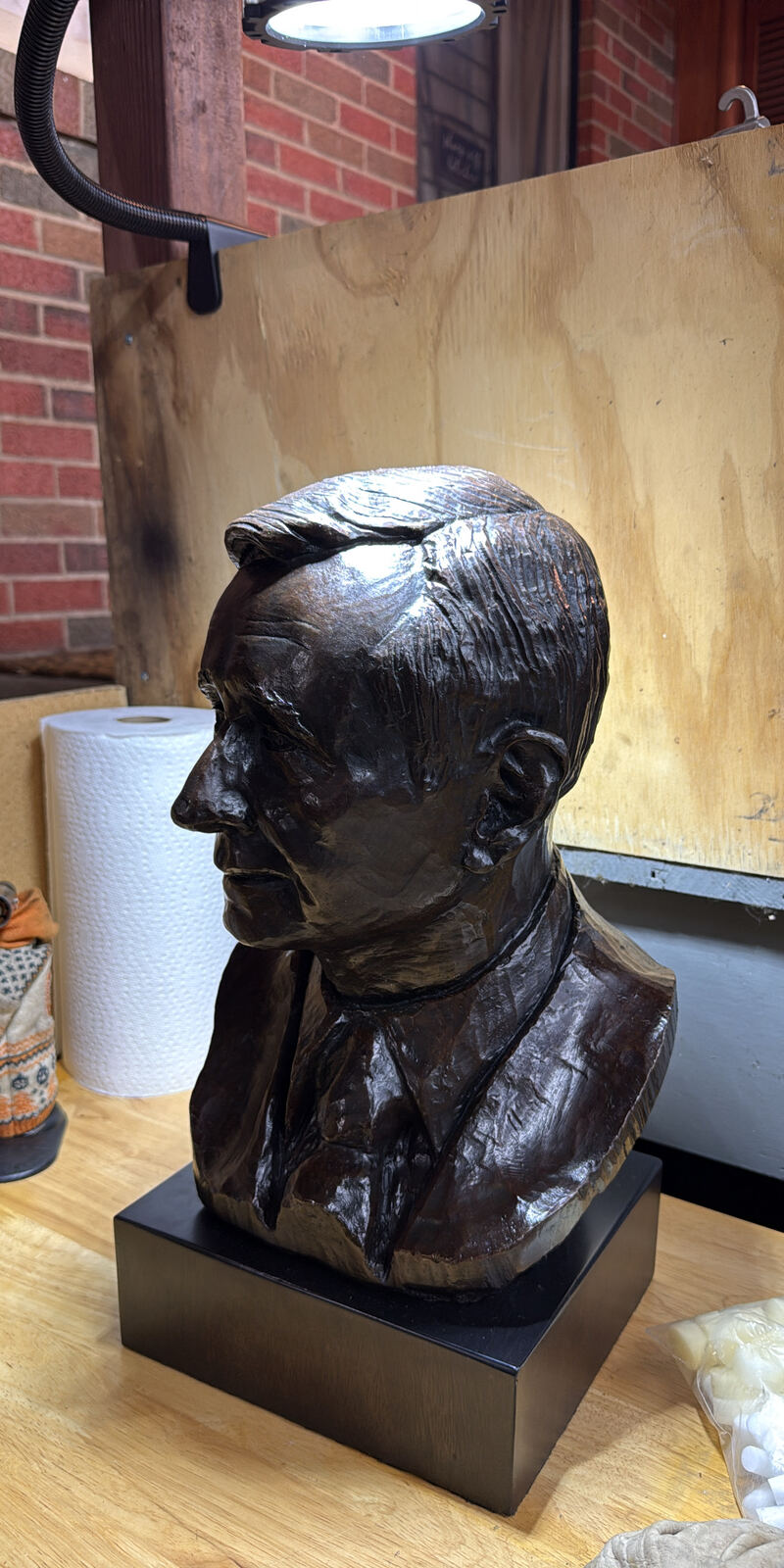Bronze portrait bust of a man in a suit and tie on a dark base